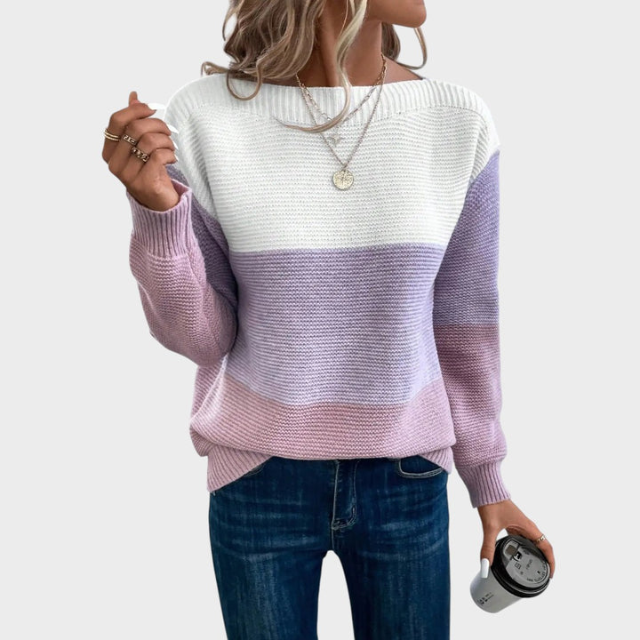 Mulher a usar camisola de malha Lars Hamburg com blocos de cores branco, lilás e rosa, decote barco e ajuste casual.