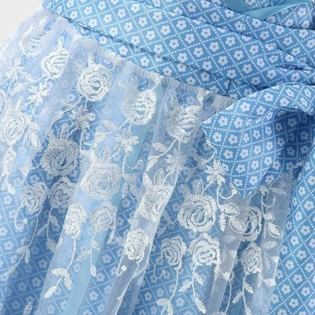 Detalhe de Dirndl Lars Hamburg azul com padrão floral e avental de renda branca com bordados de flores