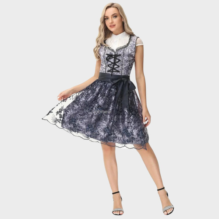 Modelo veste Dirndl Lars Hamburg cinzento e preto com detalhes em renda, corpete com laço e saia rodada para Oktoberfest
