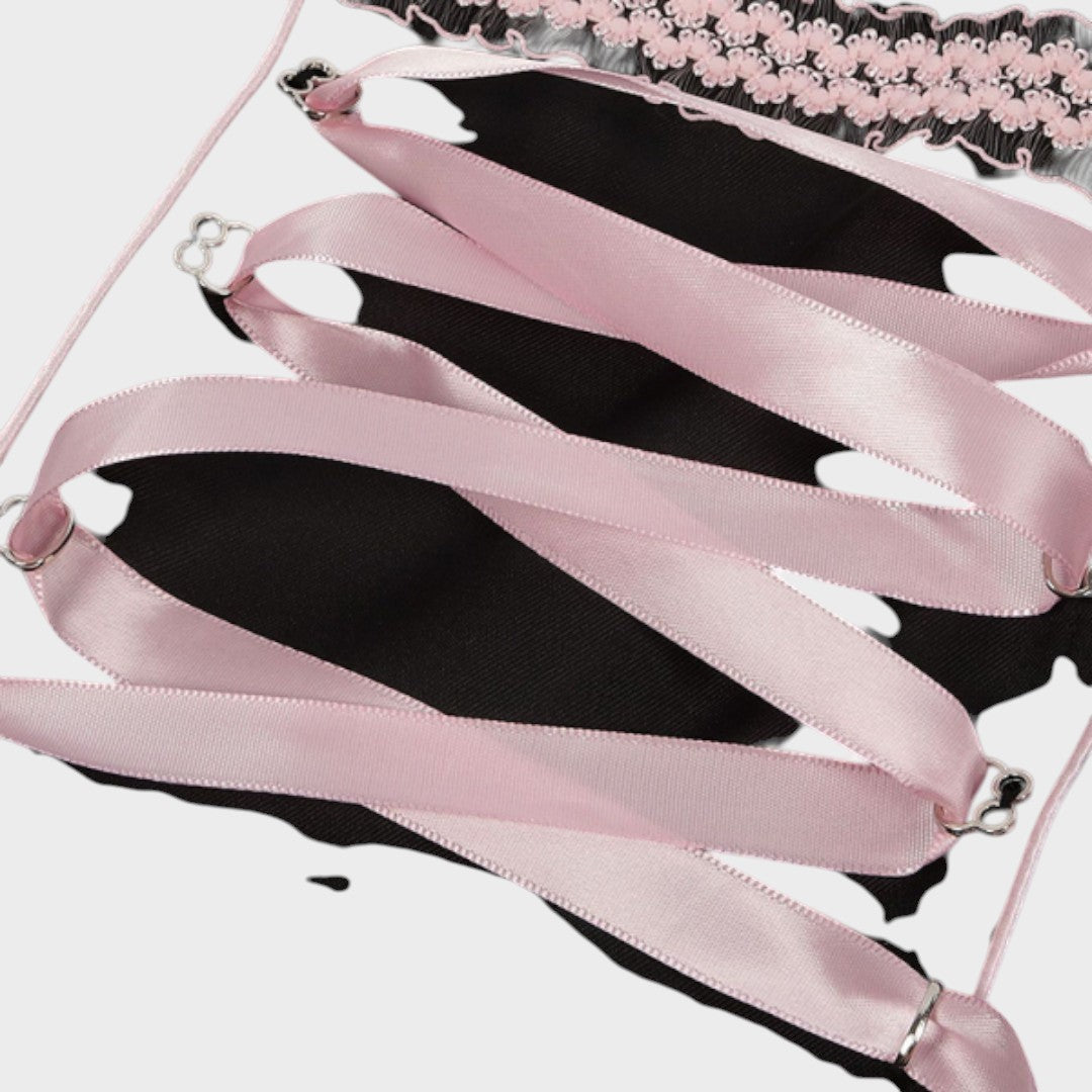 Detalhe do laço de fita rosa acetinada no corpete de um dirndl Lars Hamburg com acabamento em renda preta
