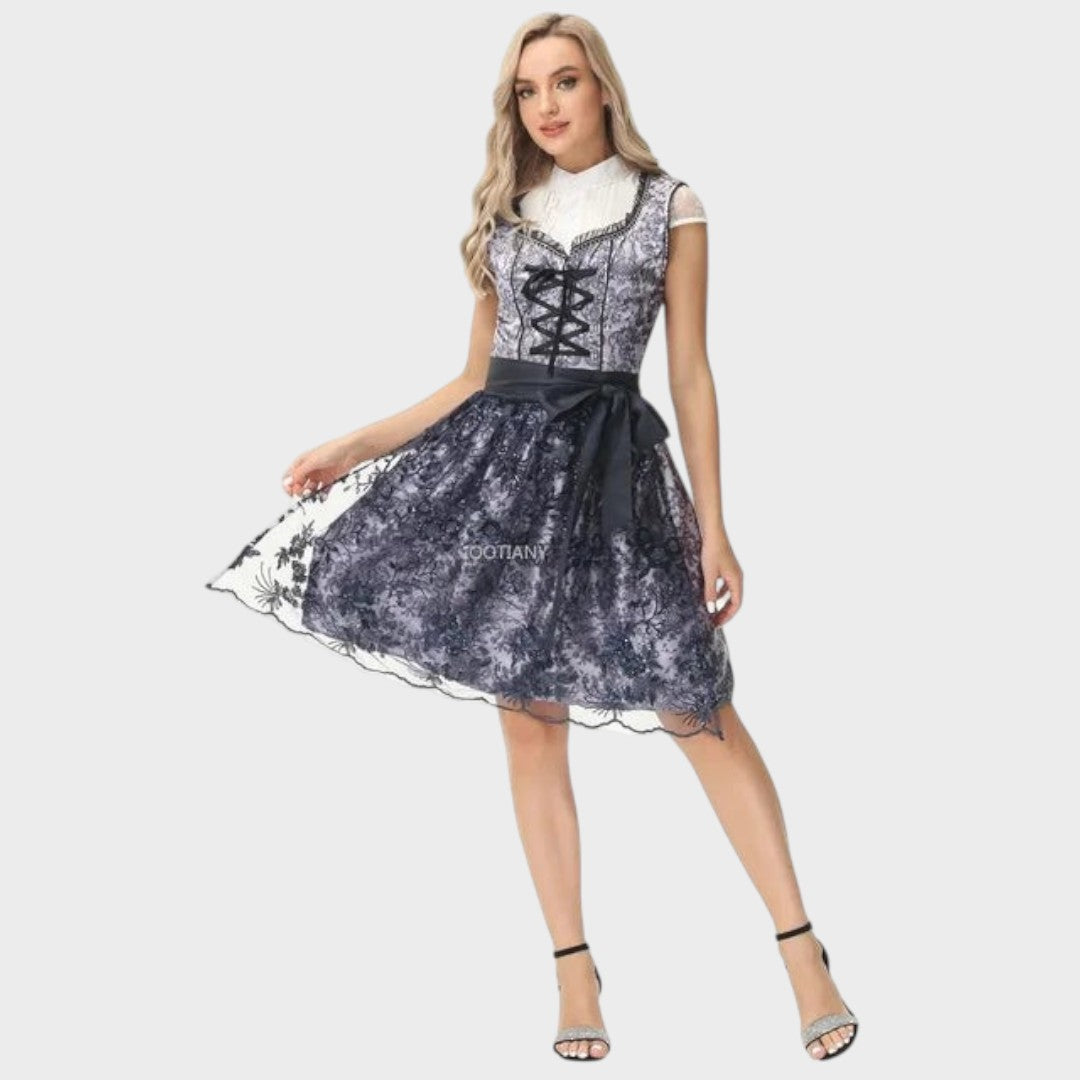 Modelo veste Dirndl Lars Hamburg cinzento e preto com detalhes em renda, corpete com laço e saia rodada para Oktoberfest