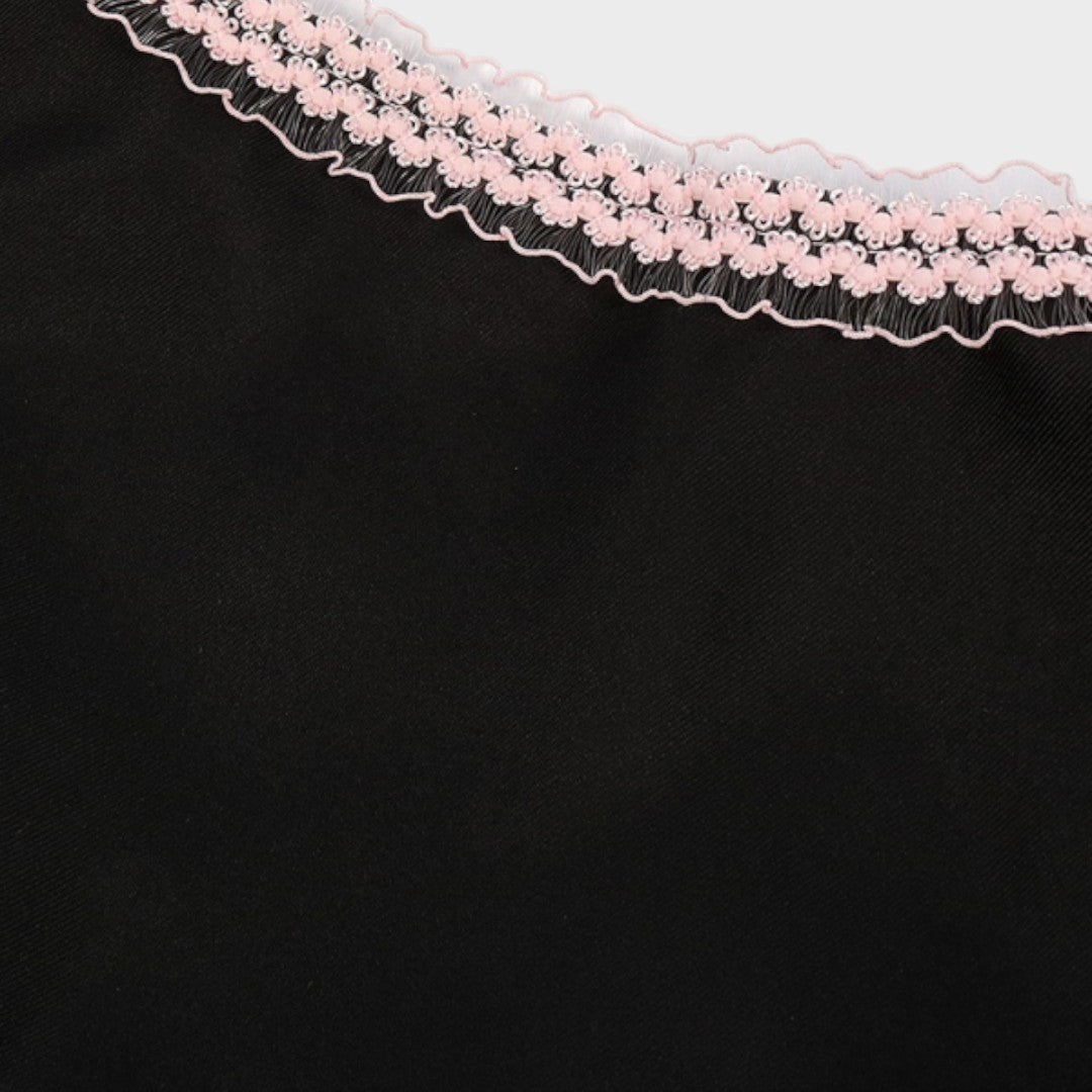 Detalhe do decote de um dirndl Lars Hamburg preto com acabamento em renda delicada na cor rosa claro