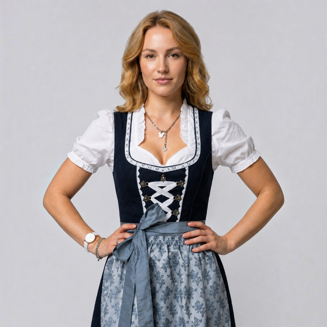 Dirndl tradicional Lars Hamburg em cinzento escuro com avental estampado, blusa branca com folhos e laço na cintura.