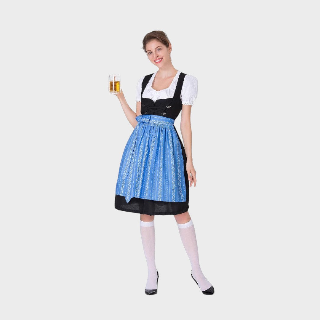 Modelo vestindo vestido tradicional Lars Hamburg preto com avental azul bordado e caneca de cerveja em fundo neutro