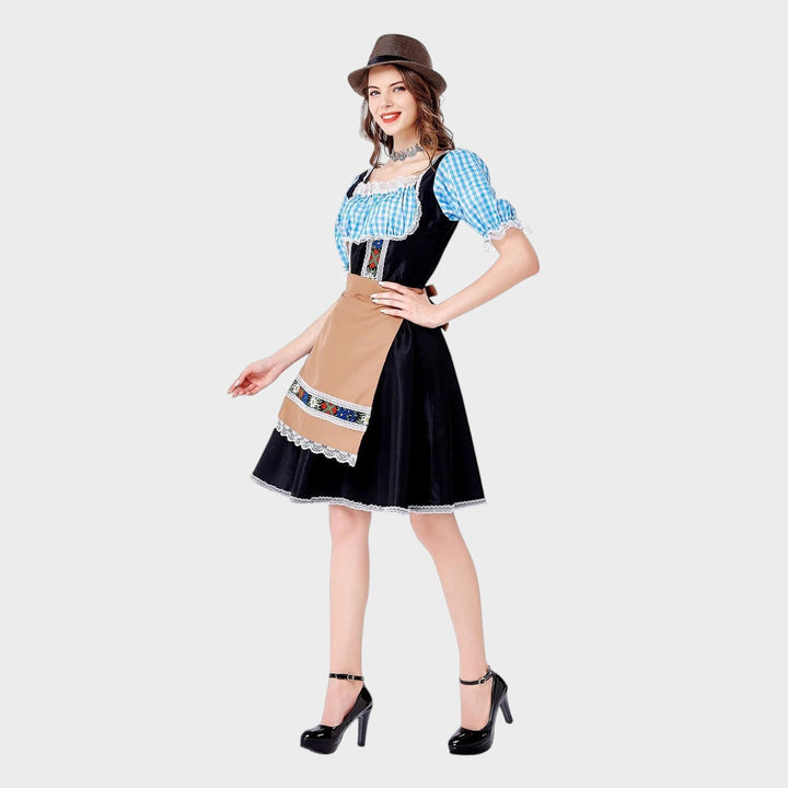 Modelo veste vestido Trachtenkleid Lars Hamburg preto com avental bege, mangas xadrez azul e detalhes bordados.