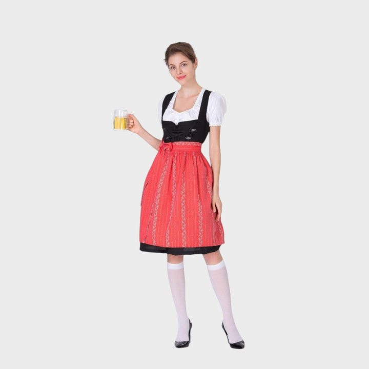 Modelo veste vestido tradicional Lars Hamburg com corpete preto, avental vermelho com bordados e blusa branca