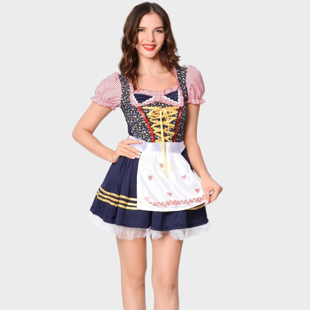 Modelo veste vestido tradicional Lars Hamburg com corpete floral, mangas xadrez, saia azul e avental branco bordado.