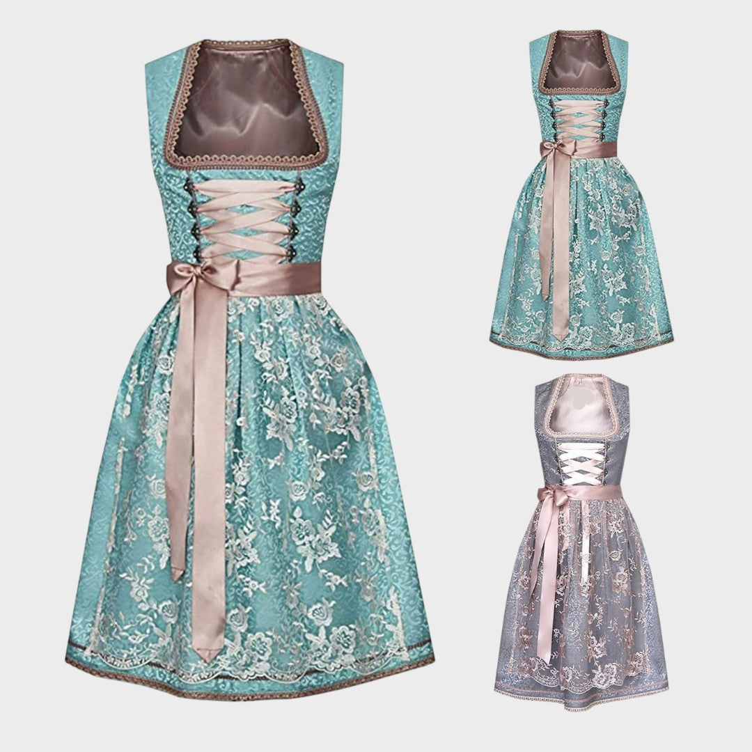 Trachtenkostüm Gretl de Lars Hamburg com avental, em tons de turquesa e cinza com detalhes em renda e laço rosa.