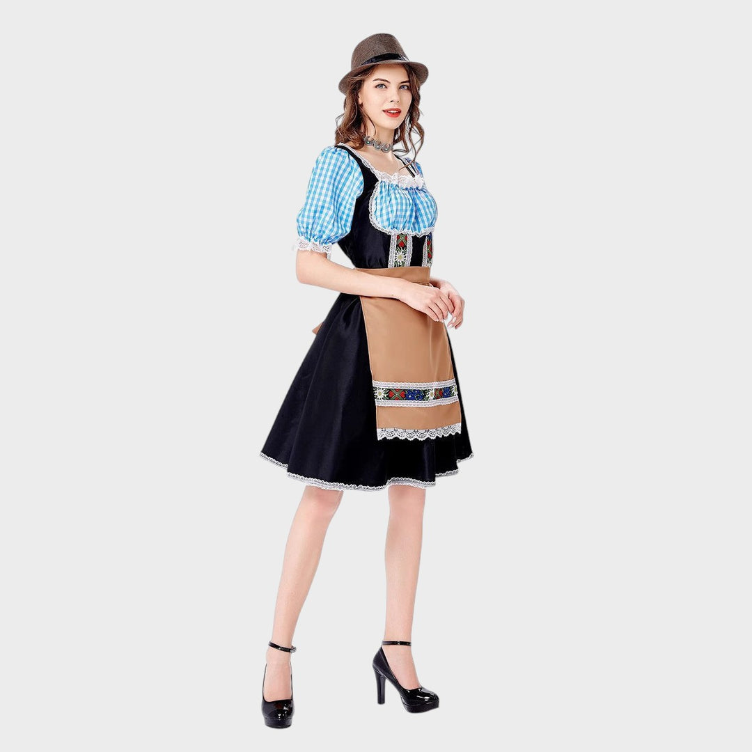 Modelo usando vestido Trachten Lars Hamburg preto com mangas xadrez azul e avental bege bordado e chapéu