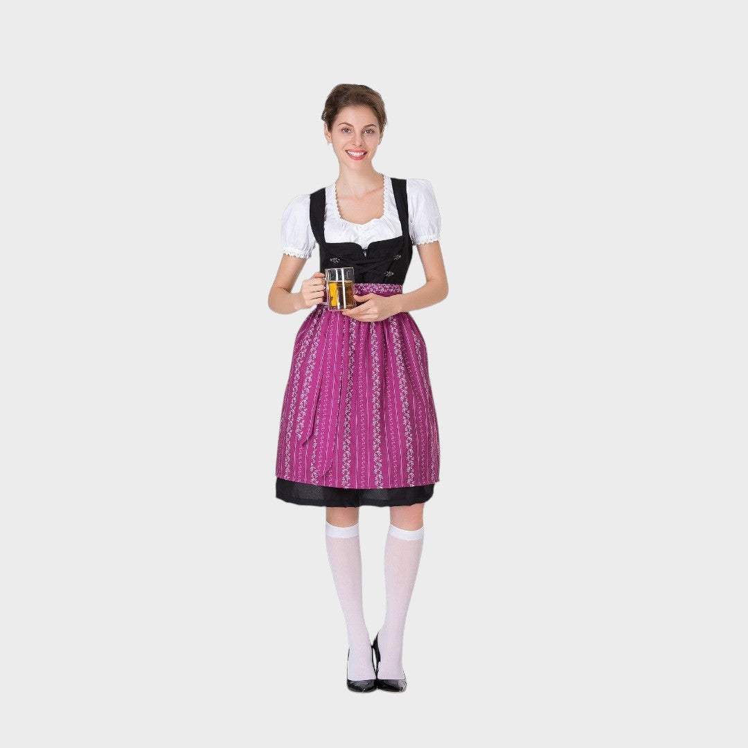 Modelo sorridente com vestido tradicional Trachten Lars Hamburg, corpete preto, avental roxo com bordados e caneca