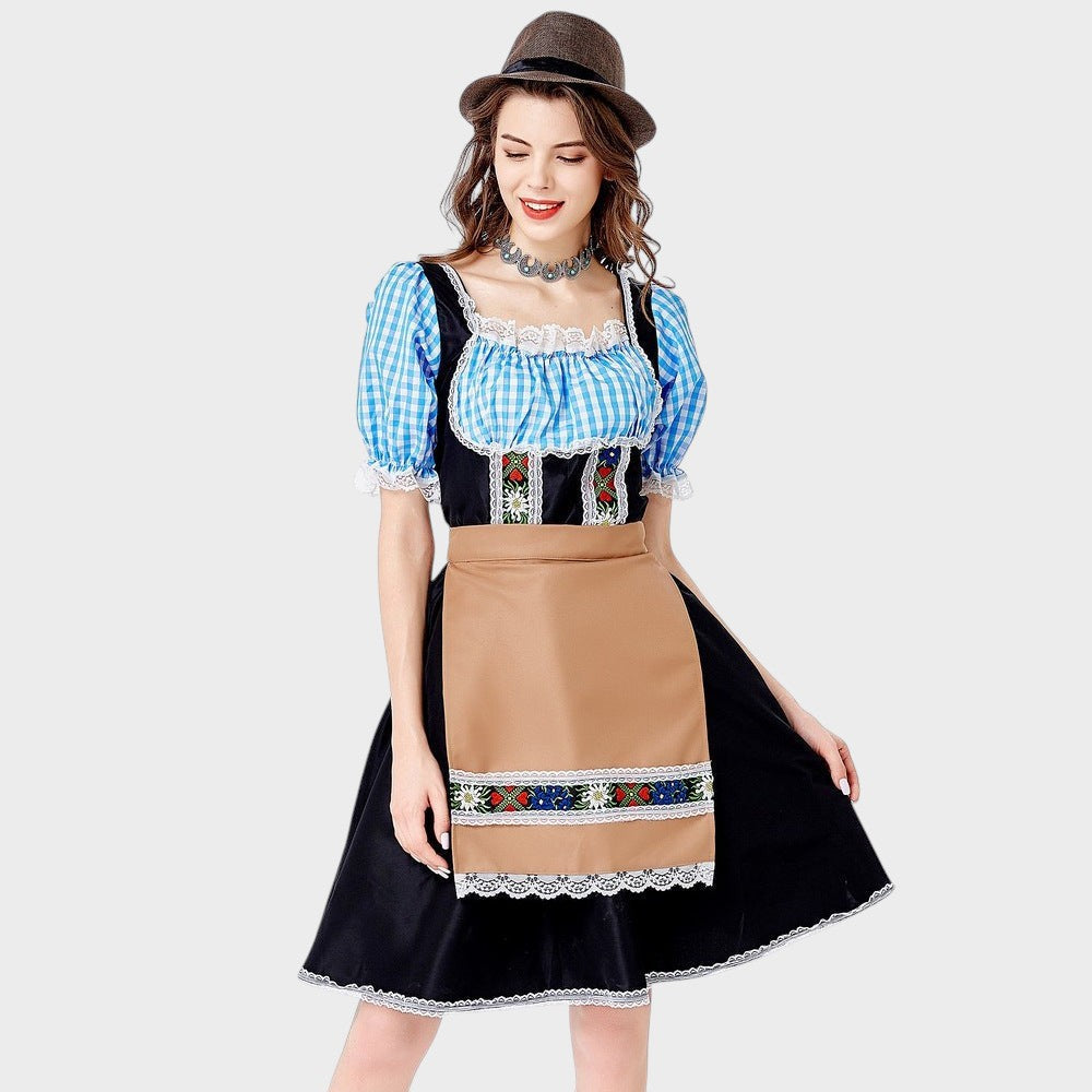 Modelo veste vestido tradicional Lars Hamburg preto com mangas xadrez azul, avental bege e detalhes bordados florais.