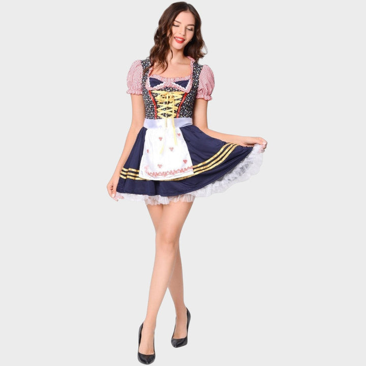 Modelo veste vestido tradicional Lars Hamburg com corpete azul, mangas xadrez rosa e avental branco com babados.