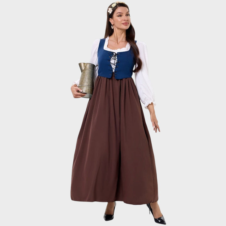 Modelo veste vestido tradicional Lars Hamburg com corpete azul, blusa branca de mangas bufantes e saia castanha longa.